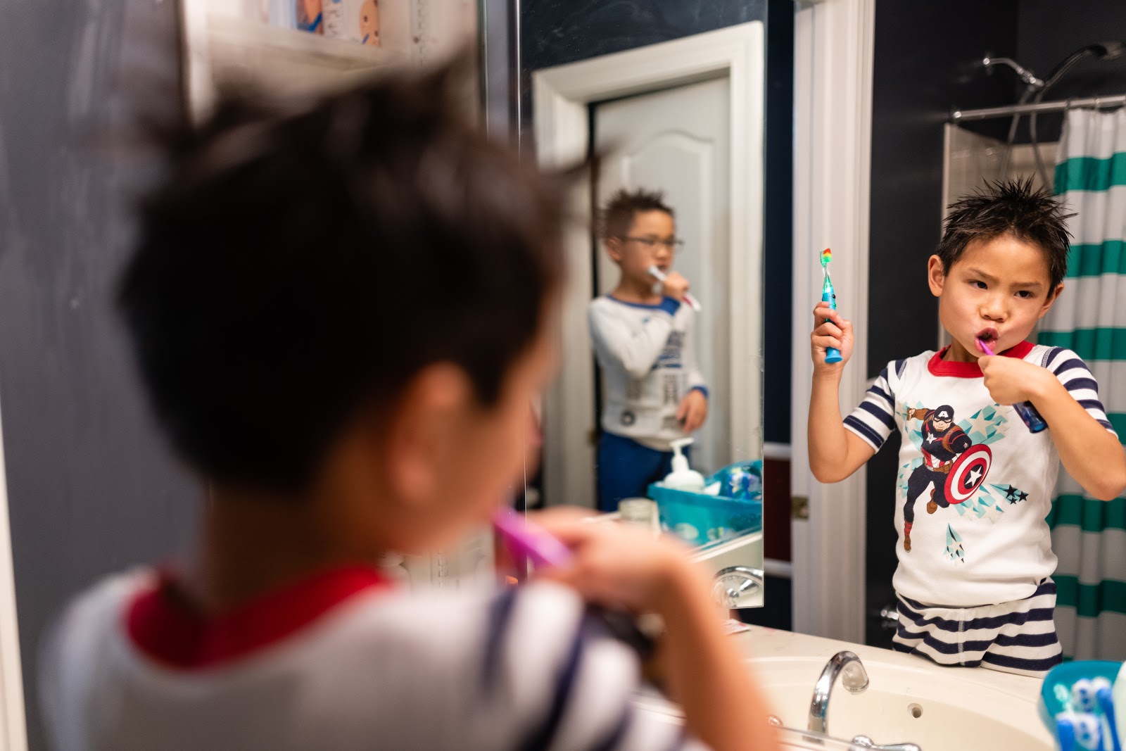 A child brushing their teeth in a mirror