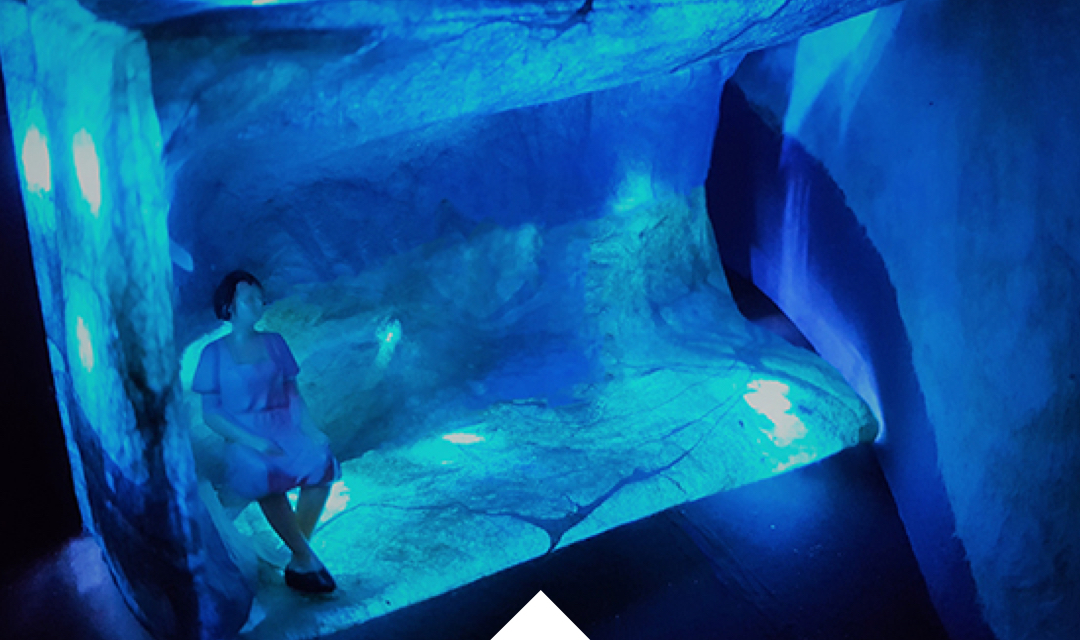 A woman sits on a bench in an underwater city