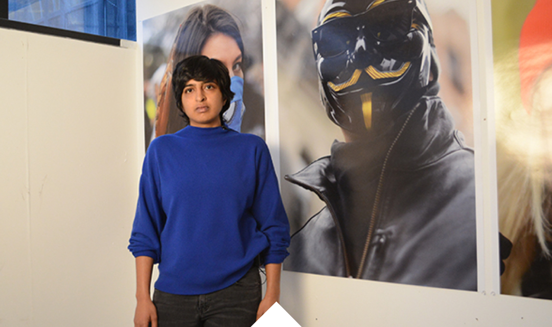 Laylaa Randera stands before large scale prints of her work