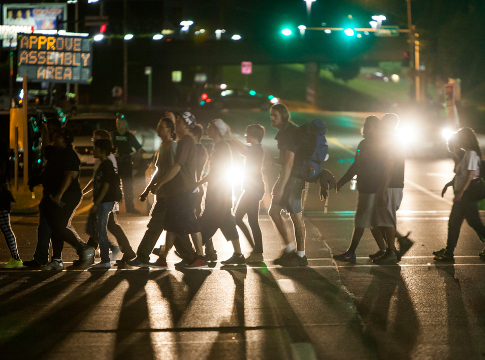 people walking across the street in the dark