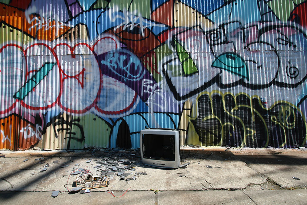 Graffiti adorns a wall behind an abandoned TV