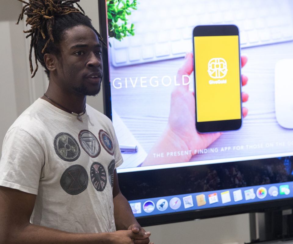 A student presents in front of a project screen