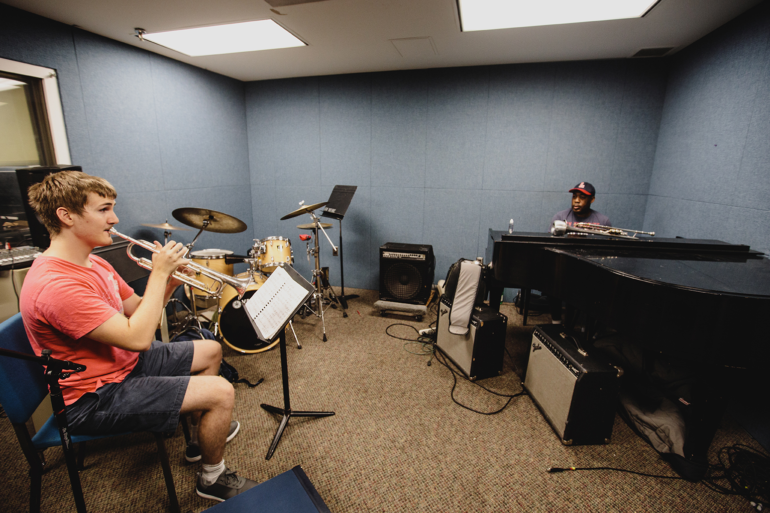Student plays trombone while instructor supervises