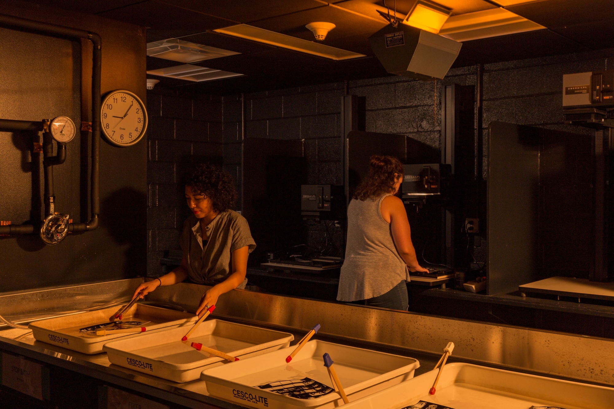 Two students develop photos in a dark lab