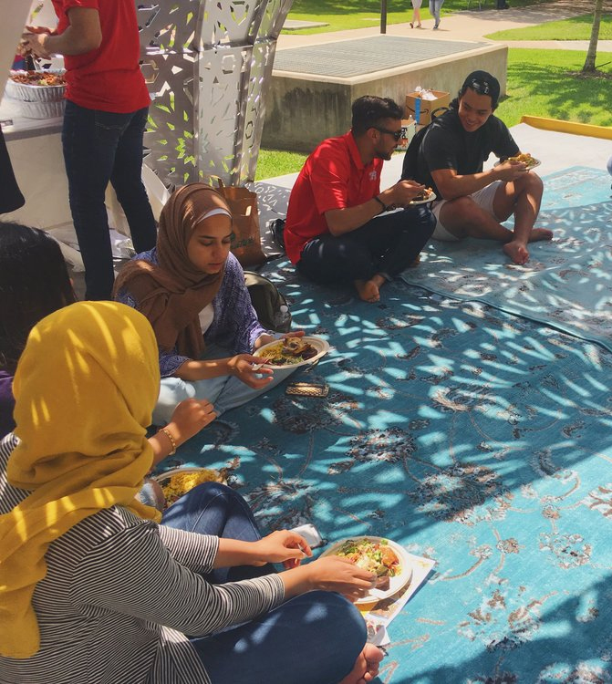 students eating on blue blankets outside at mobile mosque 