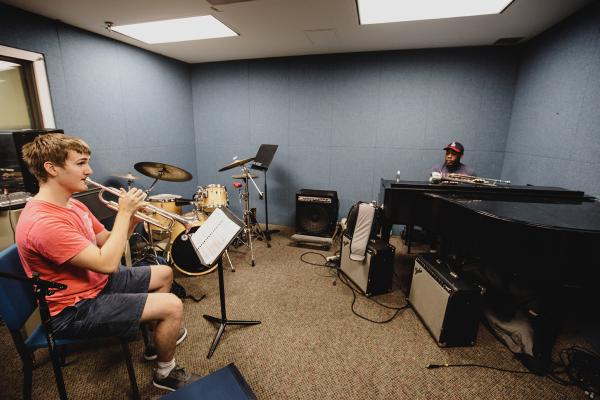 Student plays trombone while instructor supervises