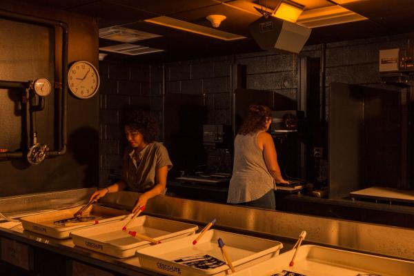 Two students develop photos in a dark lab